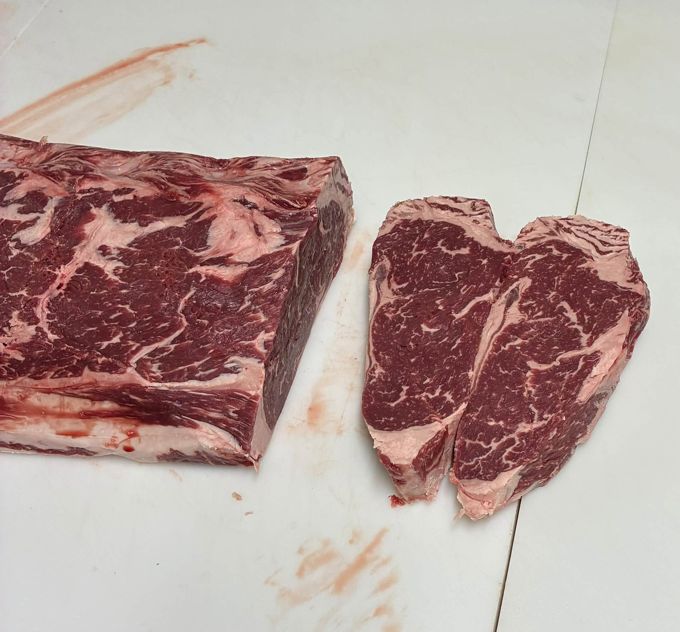 Two cut steaks beside a larger beef cut